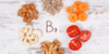 almonds, cashews, tomatoes, and carrots on a table which are a good source of biotin