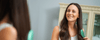 Woman brushing her hair while looking in a mirror and using hair growth tips