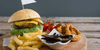 Burger, onion rings, and fries on a table which are not part of a heart healthy diet