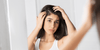 Woman looking at her hair in the mirror wondering how to repair damaged hair