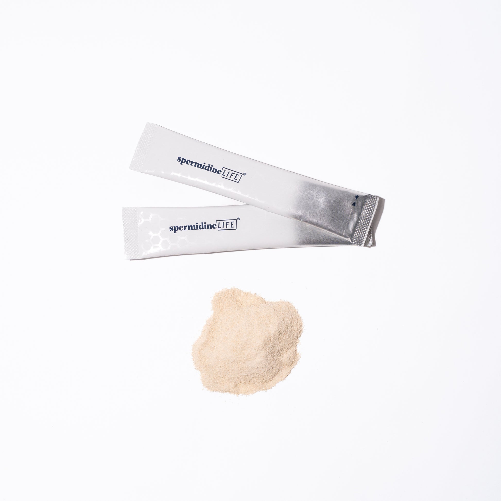 Two silver packets of spermidineLIFE® Pro+ 4300mg 30-Pack by Longevity Labs, Inc are placed beside a small pile of beige spermidine-rich powder on a white background.