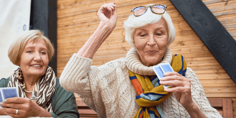 Two older ladies playing cards and enjoying a healthy life from taking spermidine, an anti-aging vitamin