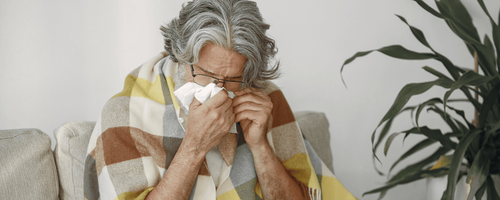 Older woman blowing her nose dealing with a weakened immune system