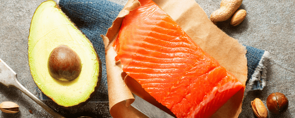 Salmon and avocado on a table which are part of a heart healthy diet