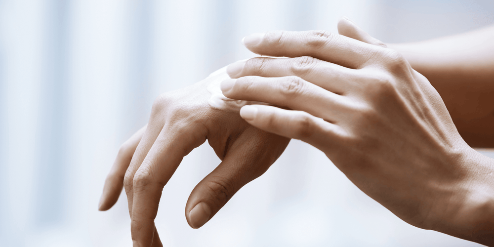 Woman rubbing lotion on her hands to take care of her skin