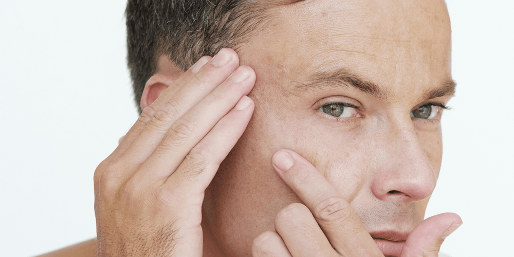 Man looking at his skin and wondering what causes aging