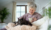 Elderly woman sitting with her cat and drinking coffee and enjoying aging in place