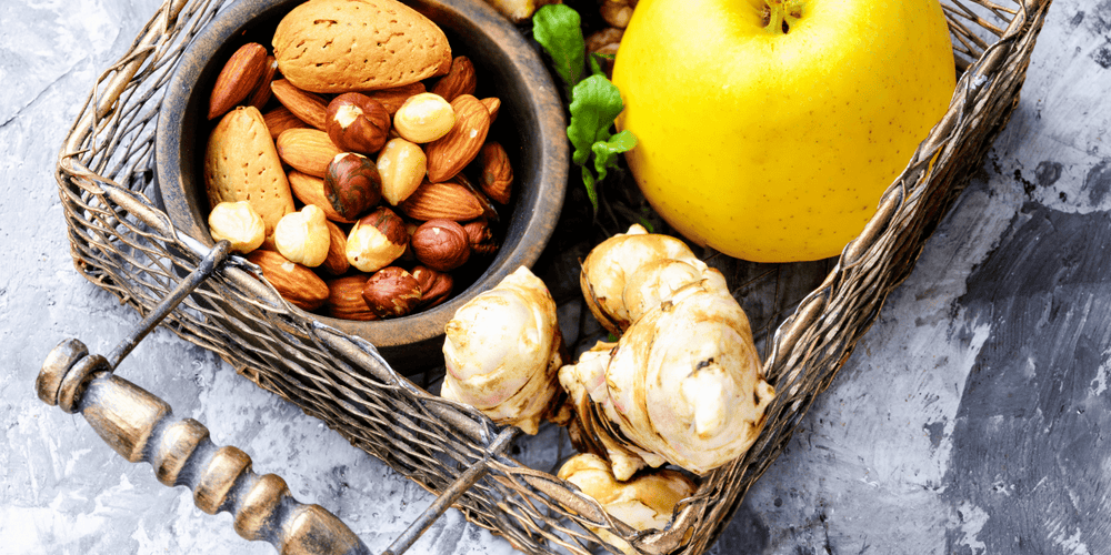 Nuts, apples, and ginger in a basket which are some of the top anti-aging foods to add to your diet