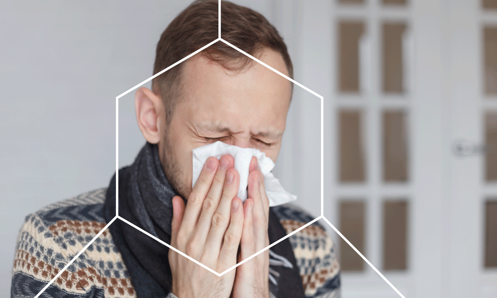Man blowing his nose which is one of the different types of human immune responses