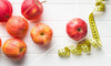 apples and a tape measure on a white background representing healthy weight loss