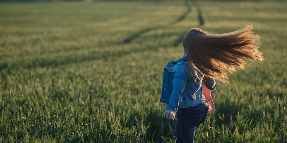 Woman swinging around her healthy hair in a wheat field