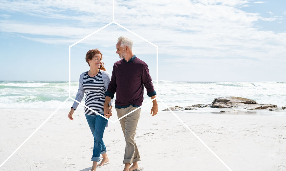 Older couple walking on a beach talking about why cellular health is important
