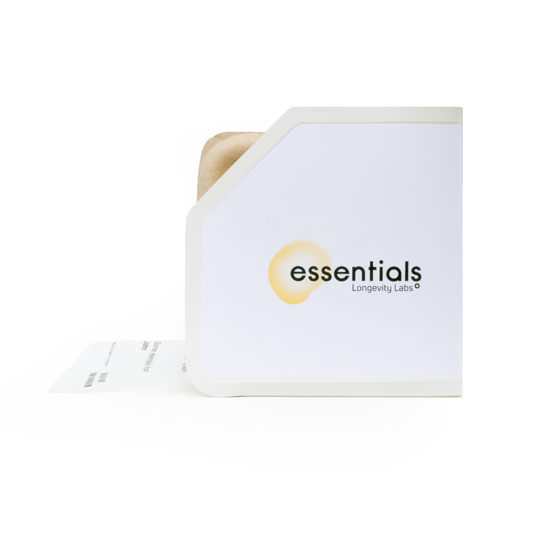 A white box labeled "Essentials autophagyCOMPLETE Multi-Pack spermidineLIFE® US" with a partially visible brown paper bag inside. A white receipt or sheet of paper extends from the bottom left corner of the box, perhaps detailing supplements like Green Tea Extract or Resveratrol+.