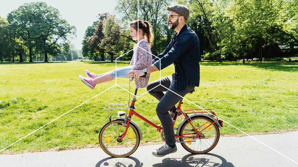A man and a girl promoting cellular health and longevity while riding a bicycle in a park.